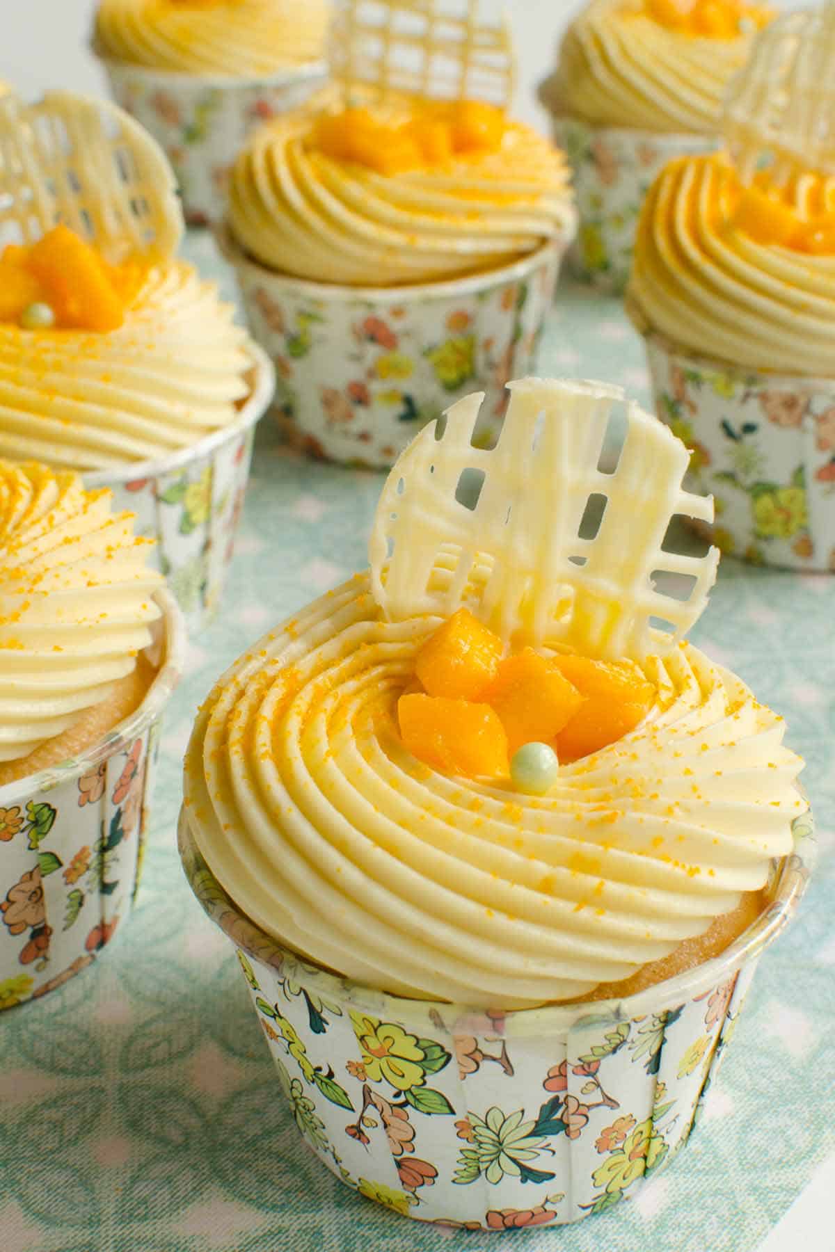Lemon cupcakes filled with mango mousse and topped with vanilla buttercream and mango chunks.