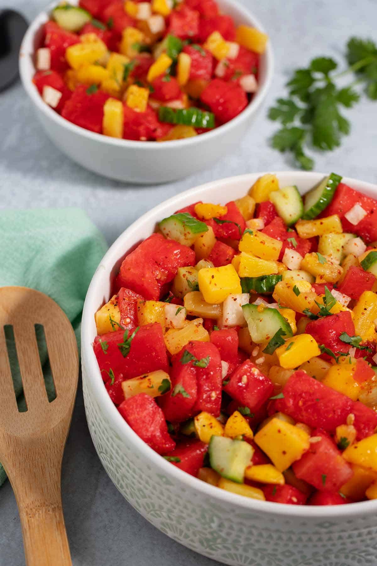 Closeup of a serving bowl full of Mexican fruit salad with serving spoon on the side.