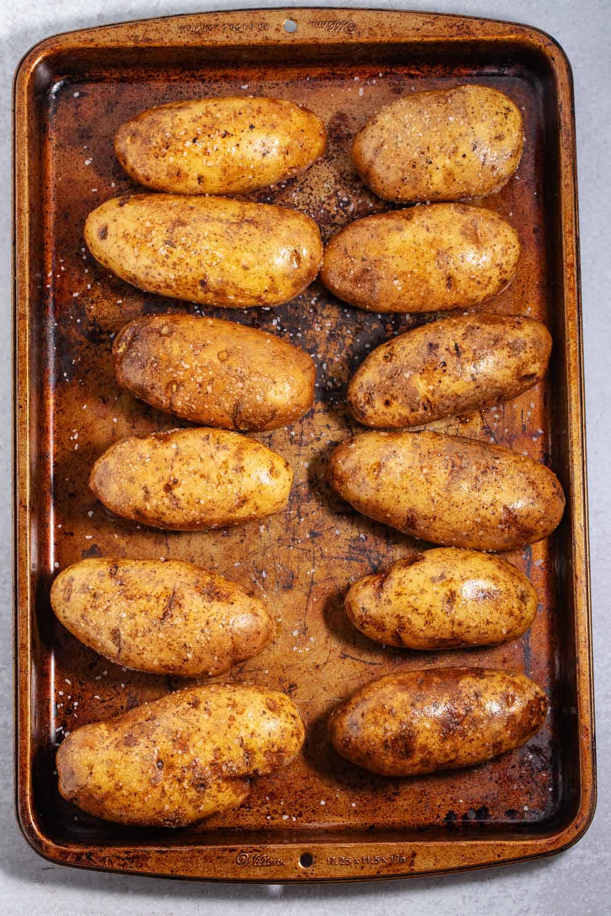 Whole potatoes on a baking pan waiting to go in the oven.