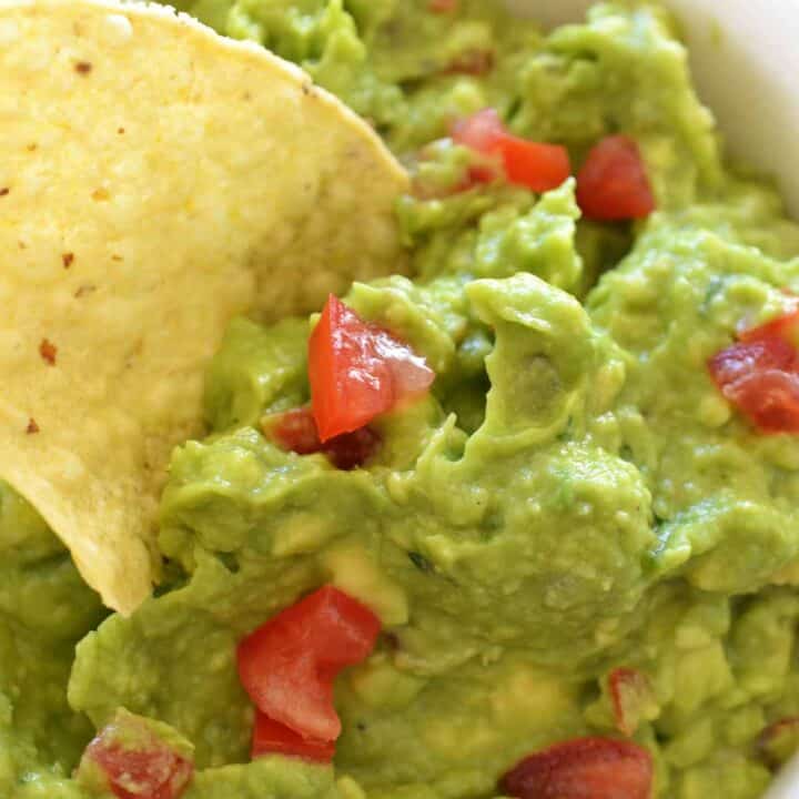 Bowl of guacamole with a chip being dunked.