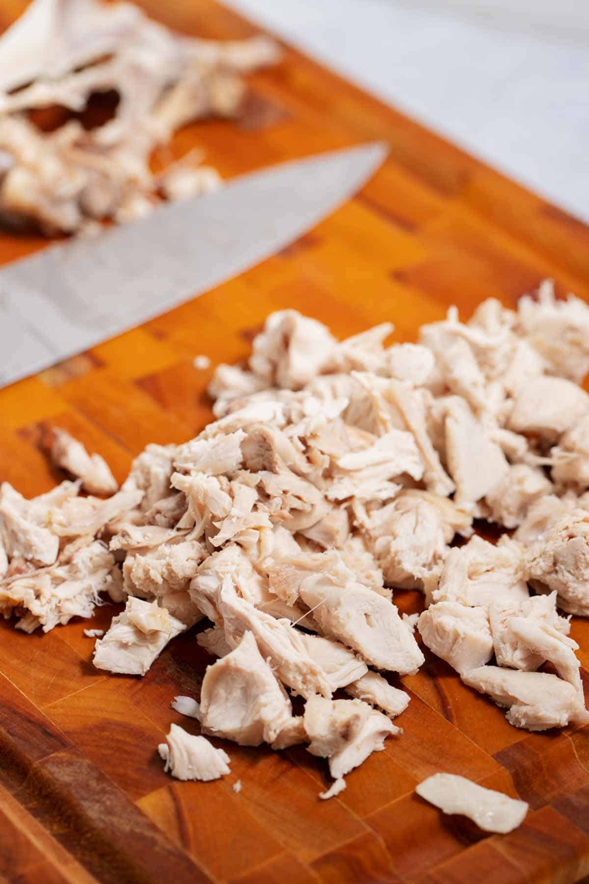 Cutting board with cut pieces of chicken that has been cooked in the Instant Pot.