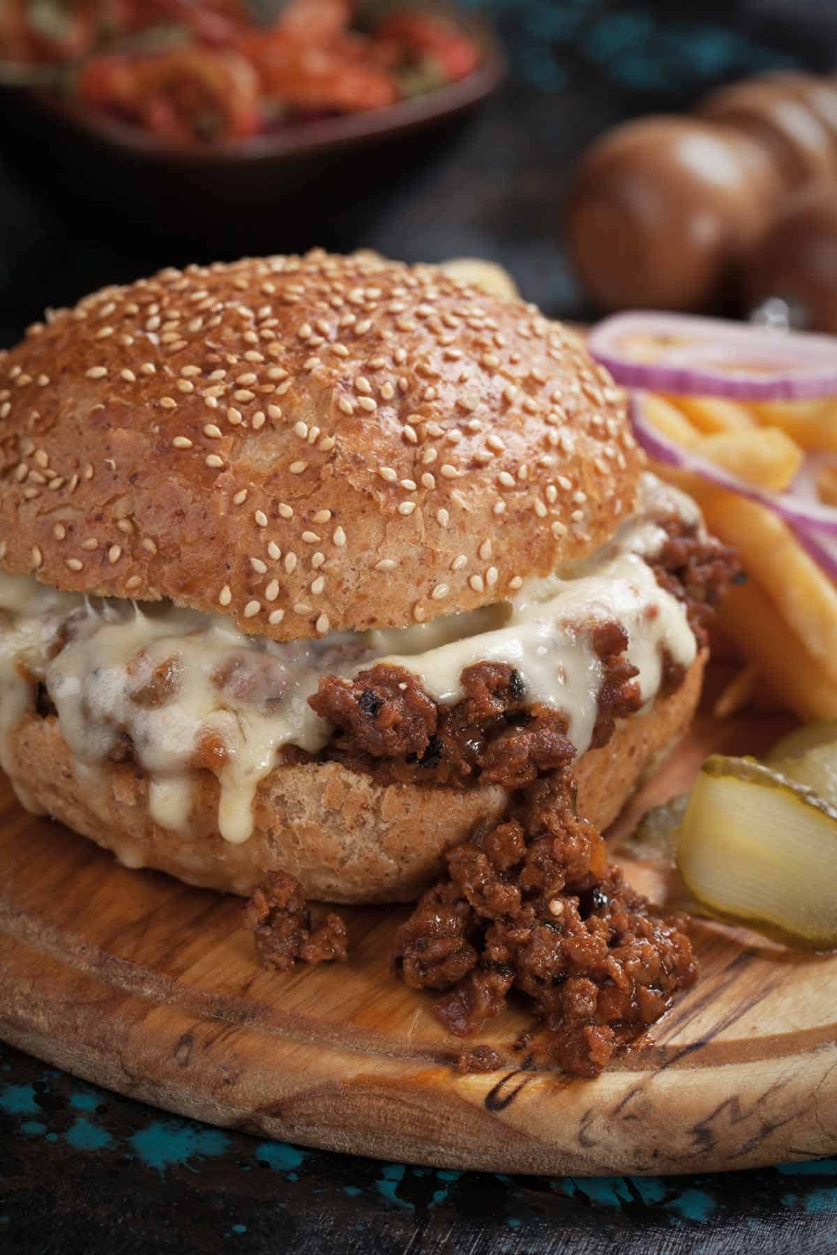 Sloppy joes sandwich with cheese on a sesame seed bun.