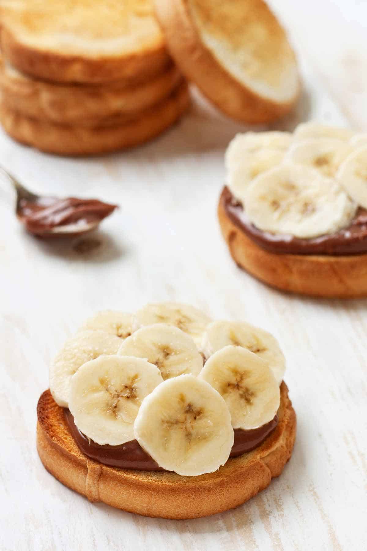 Open-faced banana nutella sandwiches on toasted bread.