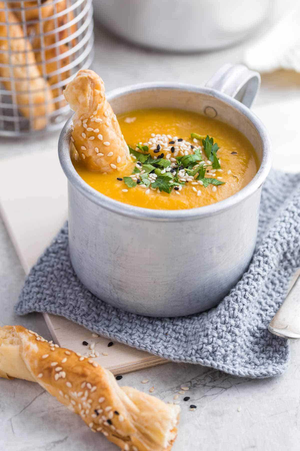 Butternut squash soup in a cup with breadsticks.