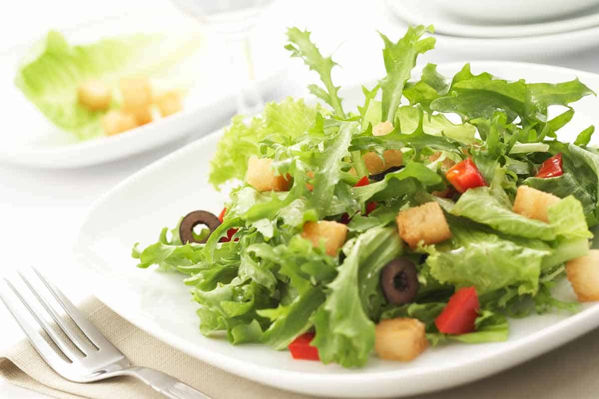 Garden salad on a plate with a fork next to it.