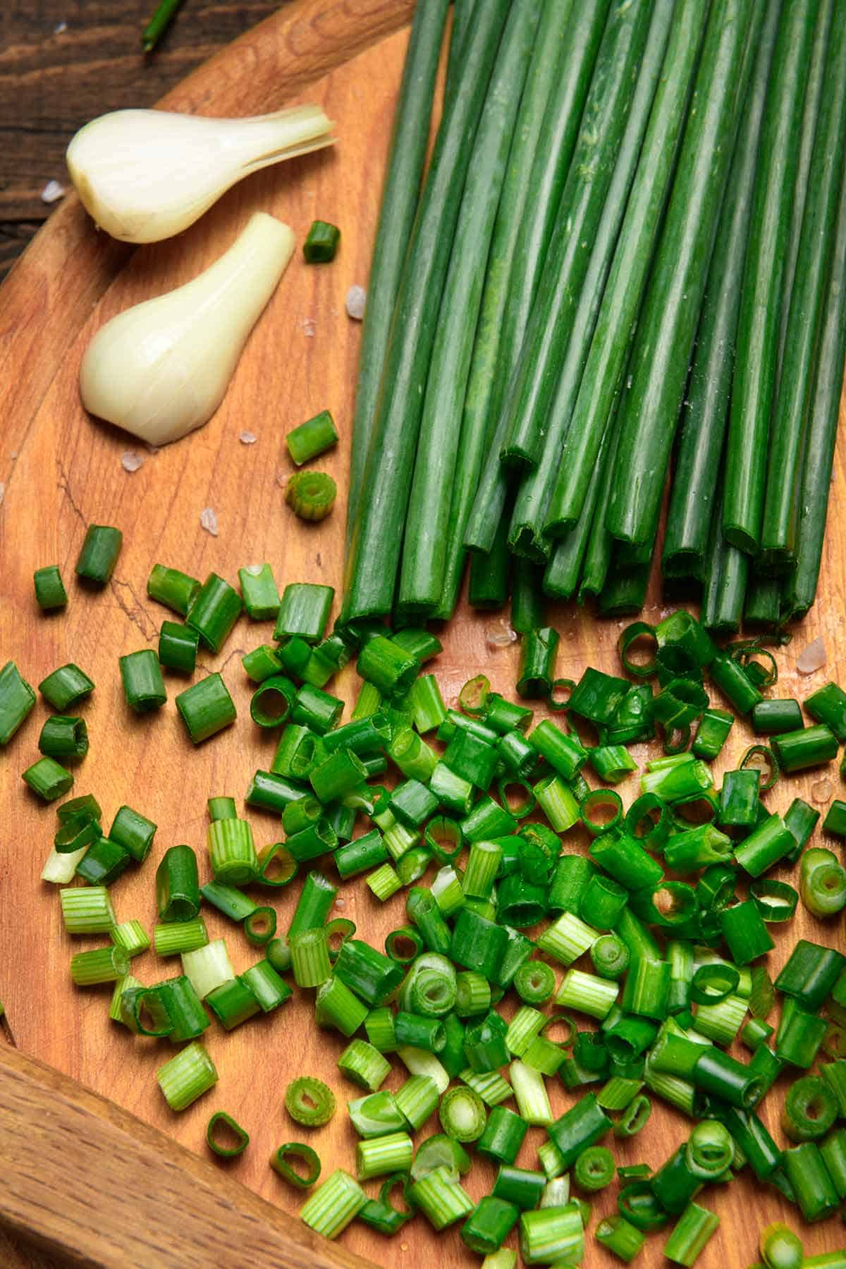 Green onions on a cutting board with some cut and some whole.