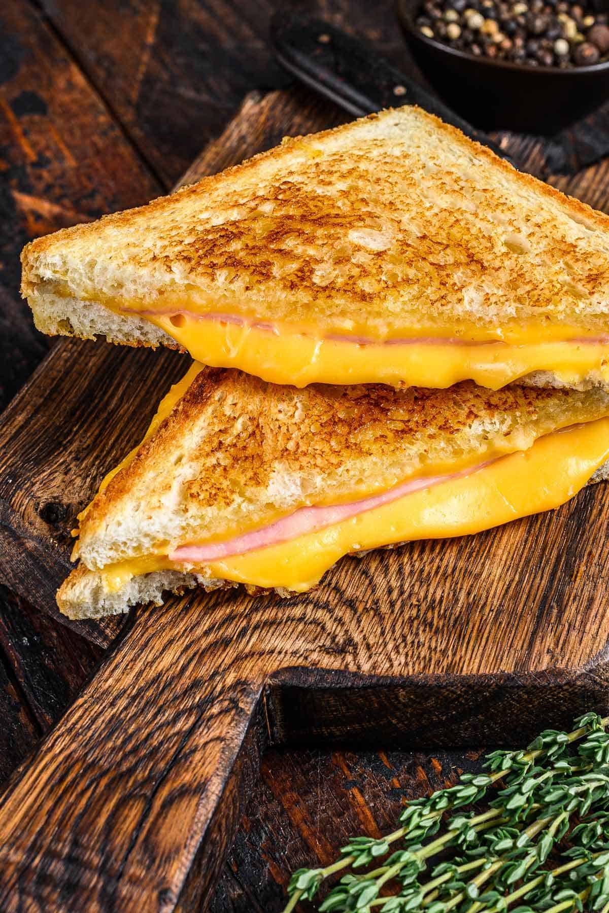 Grilled ham and cheese sandwich cut in half on a sandwich board.