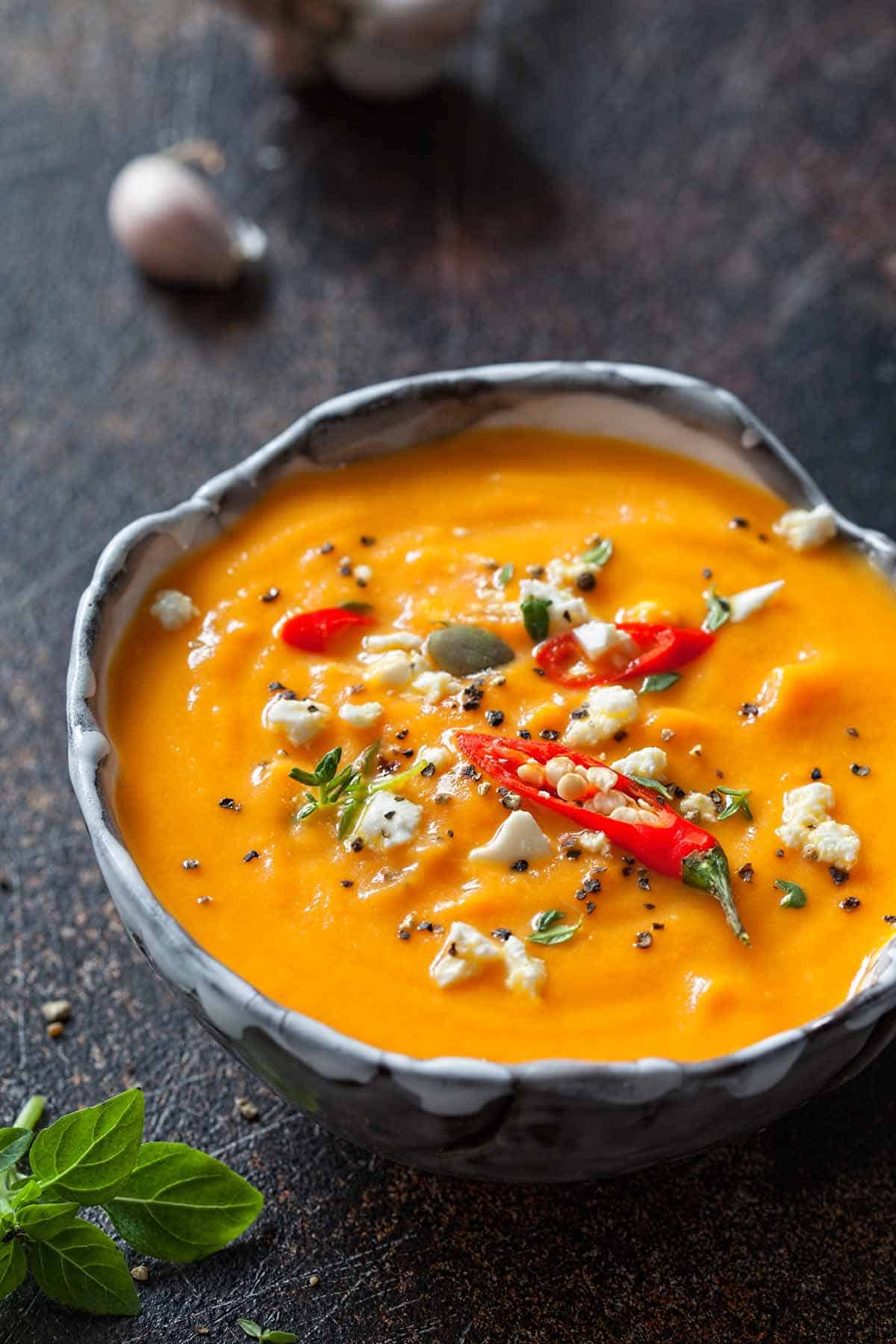 Bowl of pumpkin soup garnished with feta cheese.