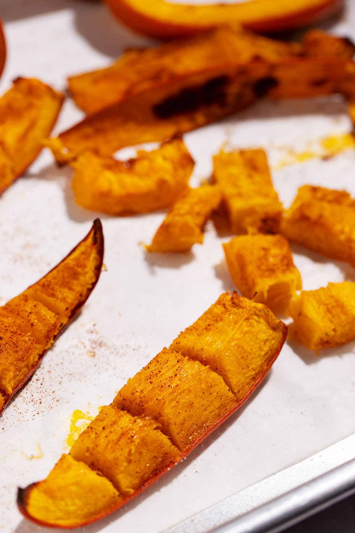 Roasted pumpkin wedge with peel cut into segments. The cut does not go through the peel, only the pumpkin flesh.