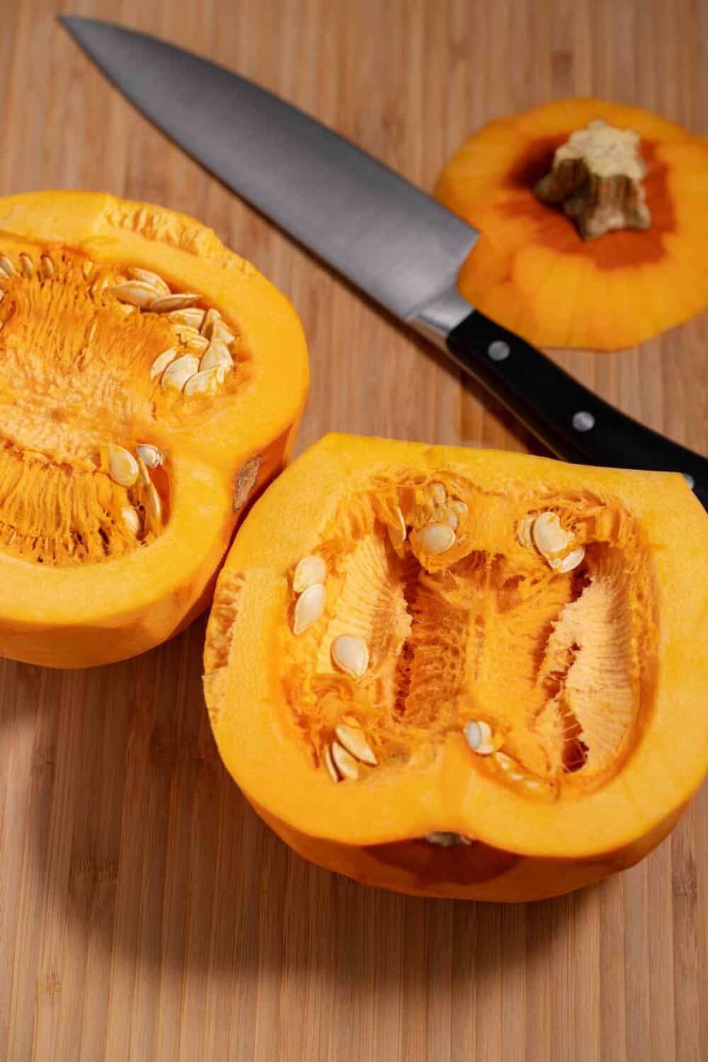 Two cut halves of a peeled pumpkin with the seeds and string still inside.