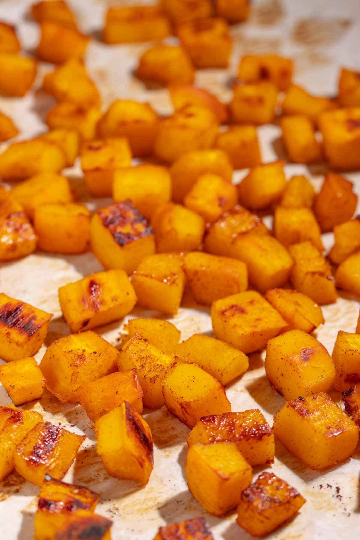 Roasted pumpkin cubes on parchment paper.