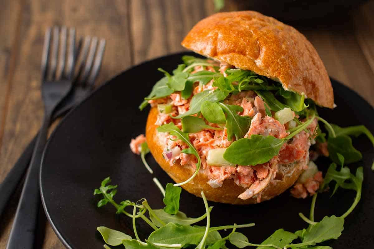 Salmon salad sandwich with arugula on a plate.