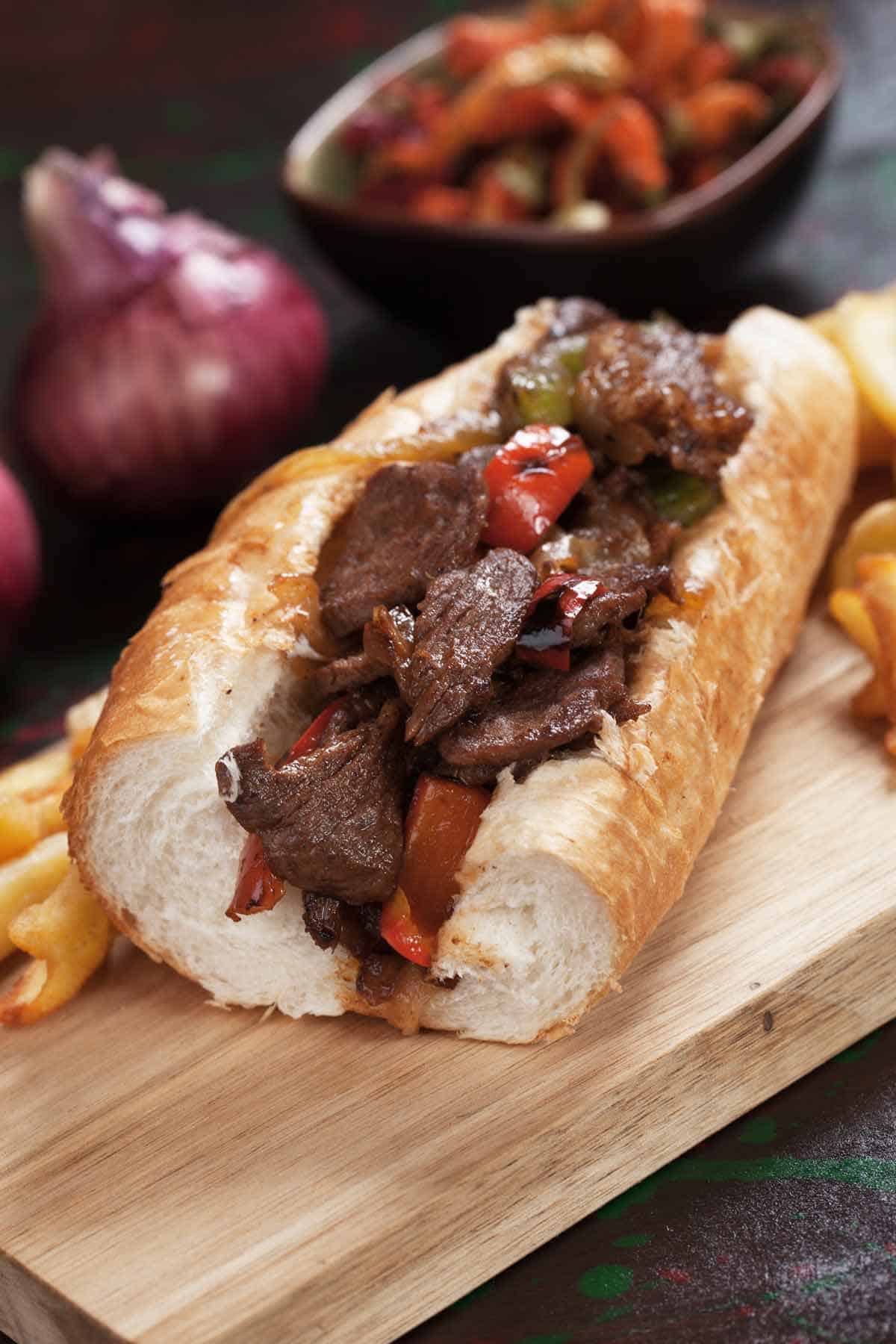 Steak sandwich on a crusty roll on a sandwich board.