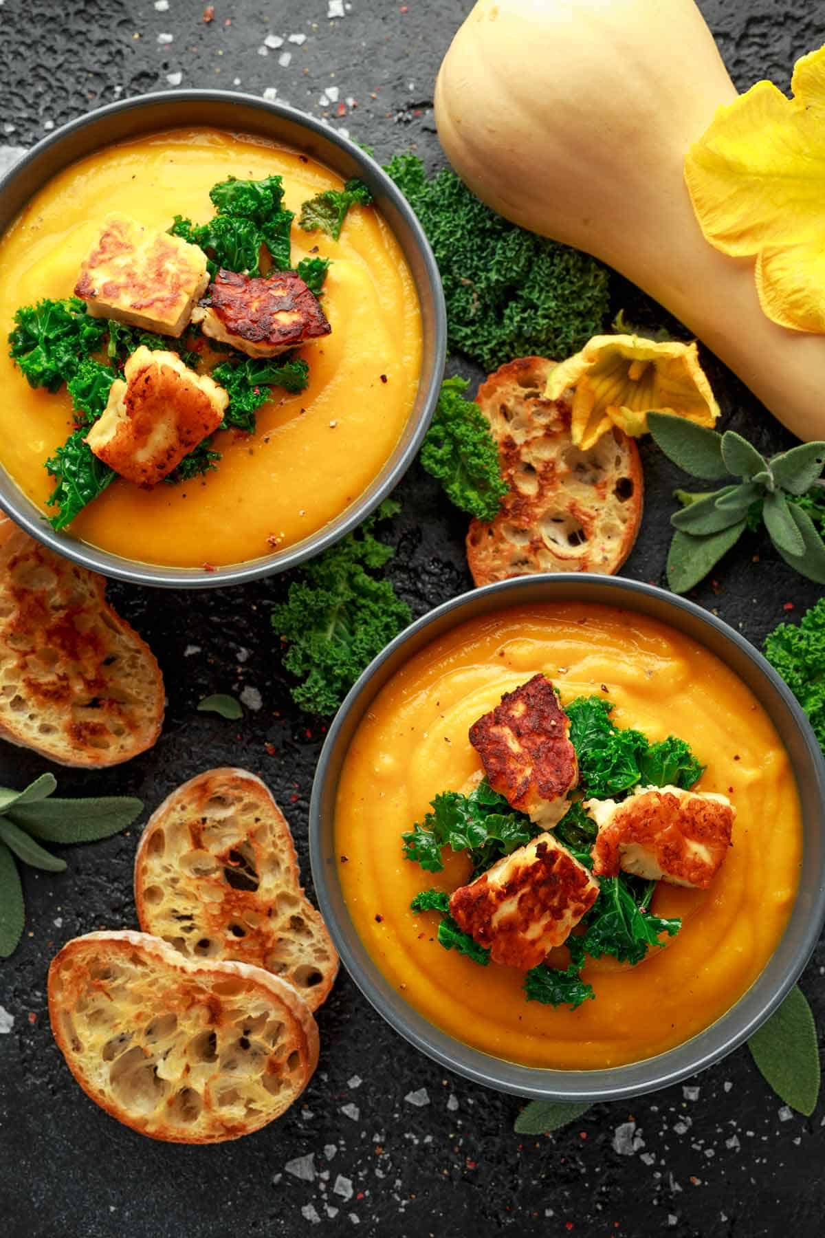 Two bowls of butternut squash soup with toasted French bread.