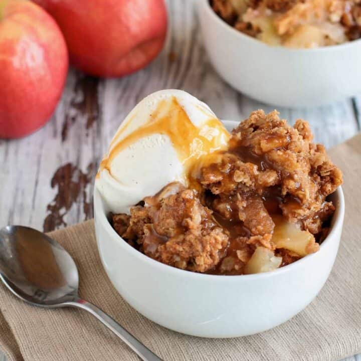Bowl of apple crisp with a scoop of vanilla ice cream.