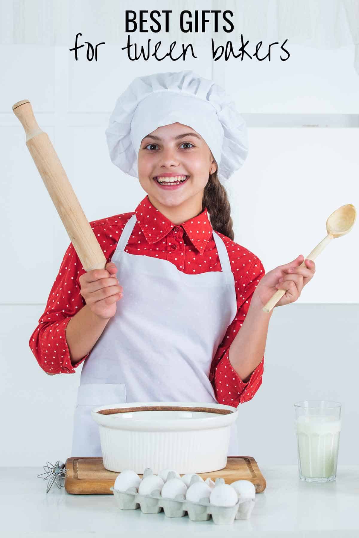 Tween girl with chef hat and apron holding a wooden spoon and rolling pin.