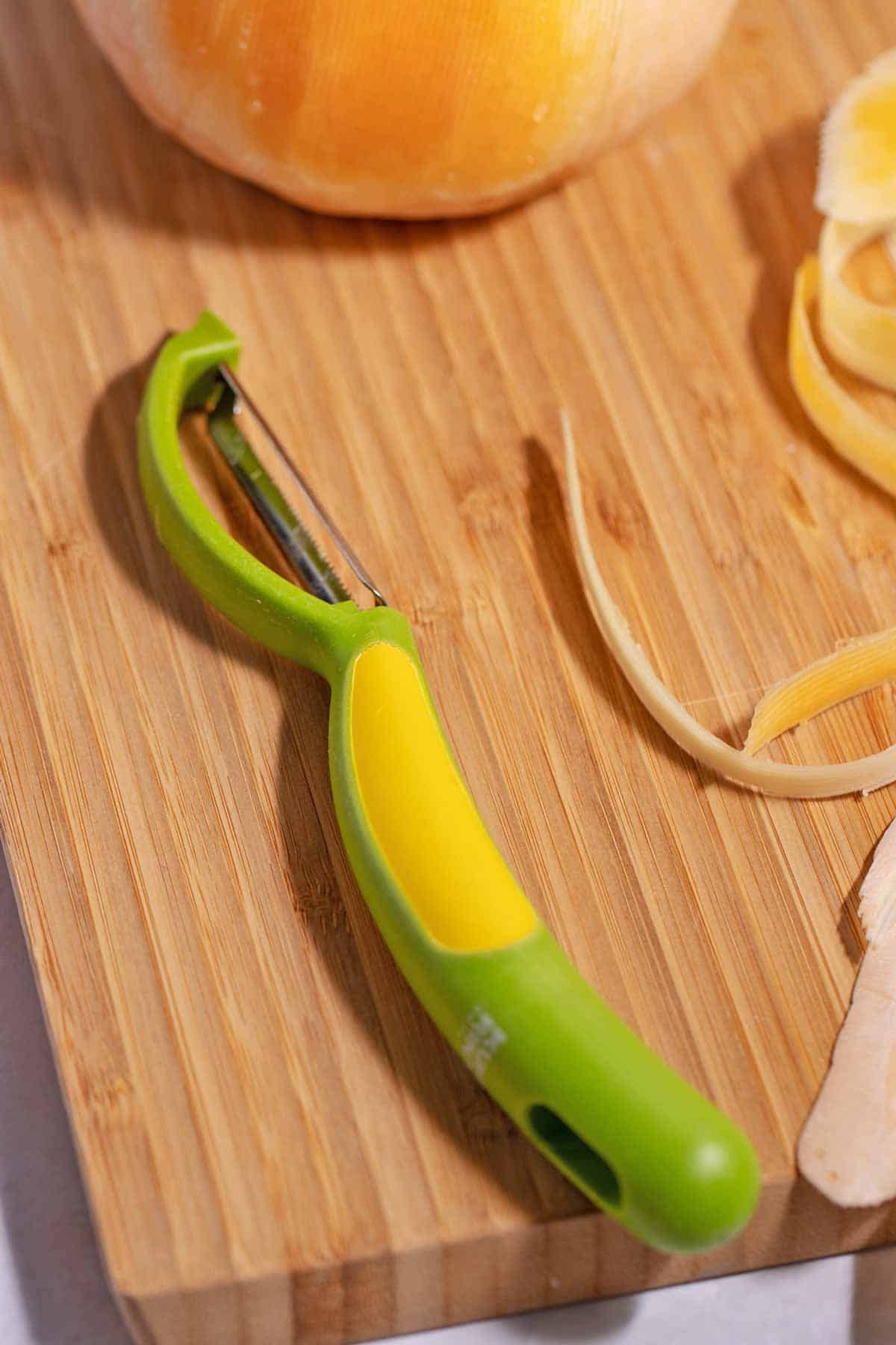 Kuhn Rikon swivel peeler on a cutting board with butternut squash.