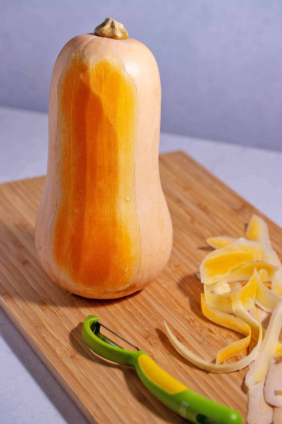 Butternut squash soup on a cutting board with a peeler.