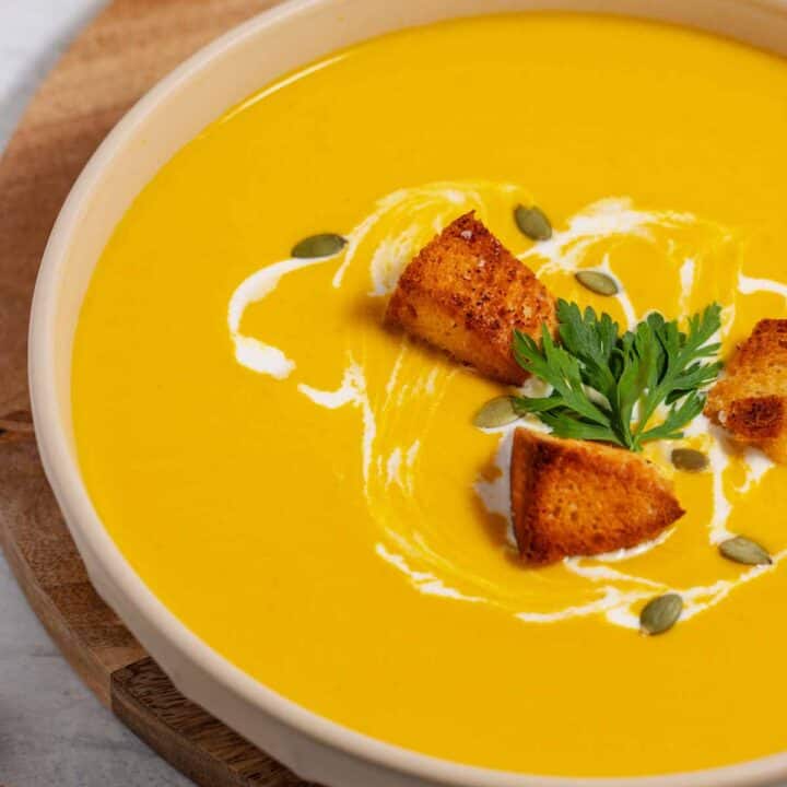 Bowl of spicy butternut squash soup with cream cheese, garnished with croutons.