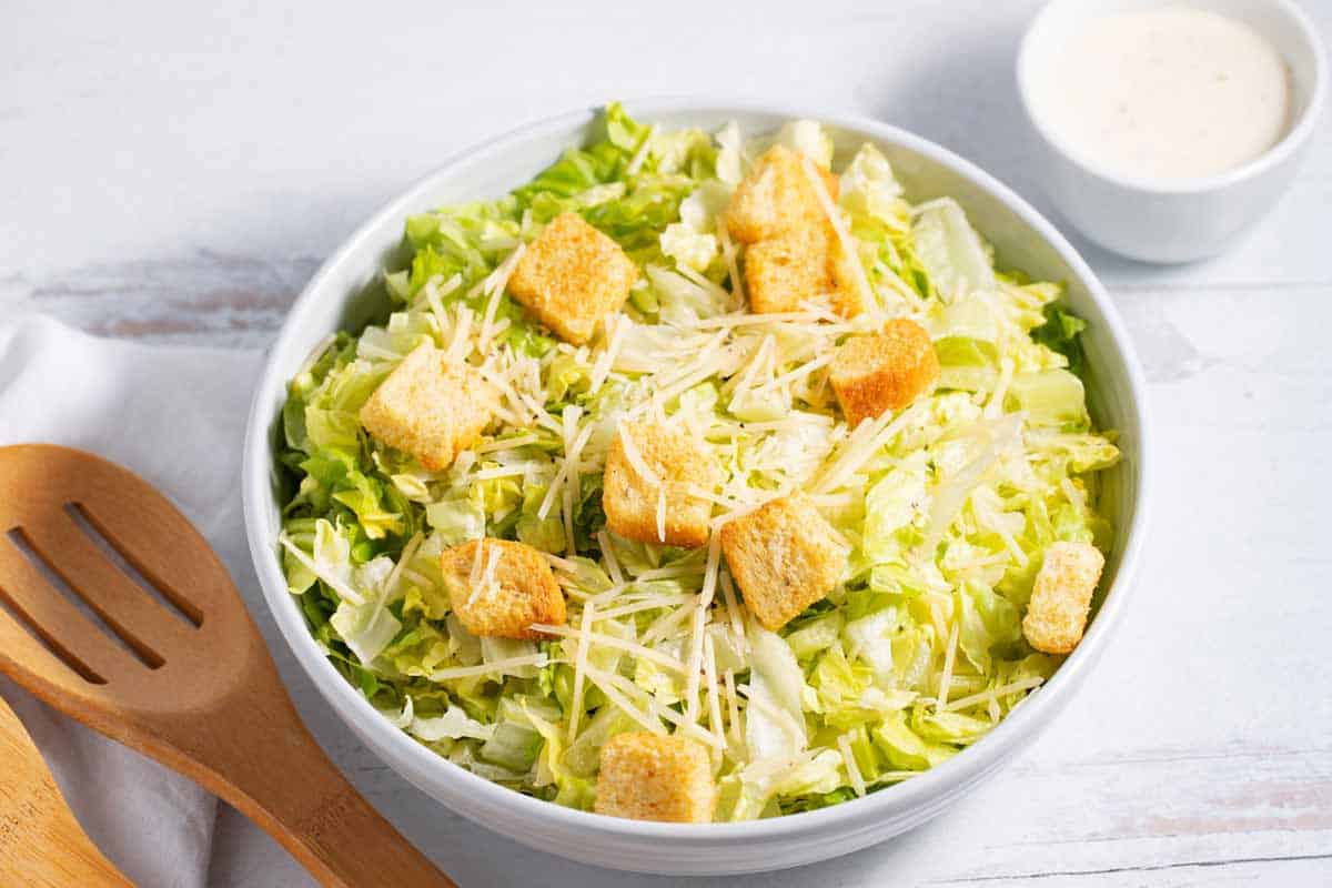 Caesar salad in a bowl with croutons and shredded Parmesan cheese.