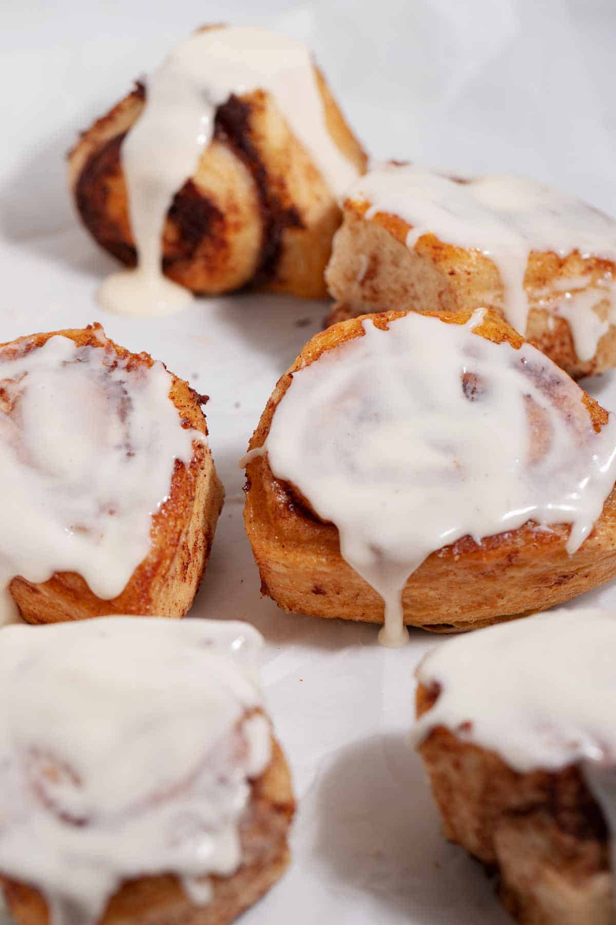 Group of cinnamon rolls with icing dripping off them.