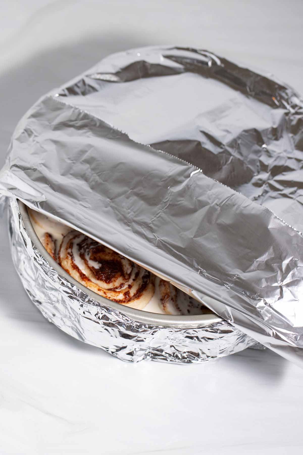 Foil covering the pan of canned unbaked cinnamon rolls.