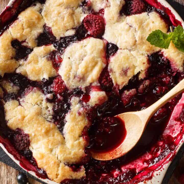 Pan of cherry and berry cobbler with a serving spoon.