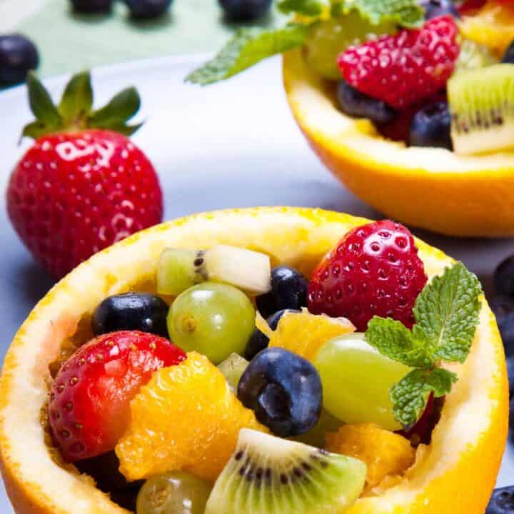 Hollowed out orange half filled with a fruit salad.