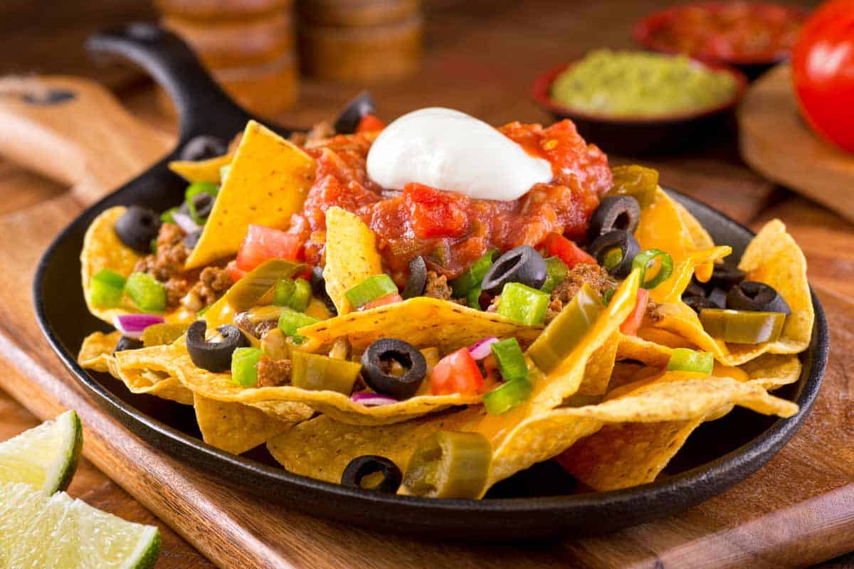 Plate of nachos with salsa and sour cream.
