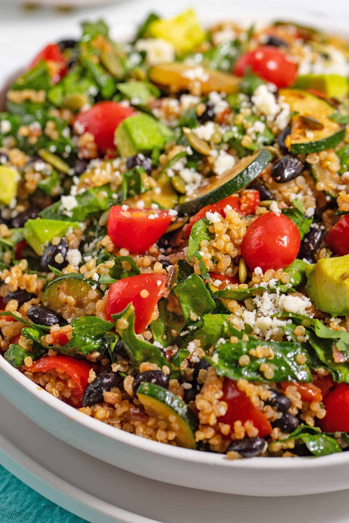 Quinoa black bean salad in a bowl with tomatoes, avocado, and zucchini.