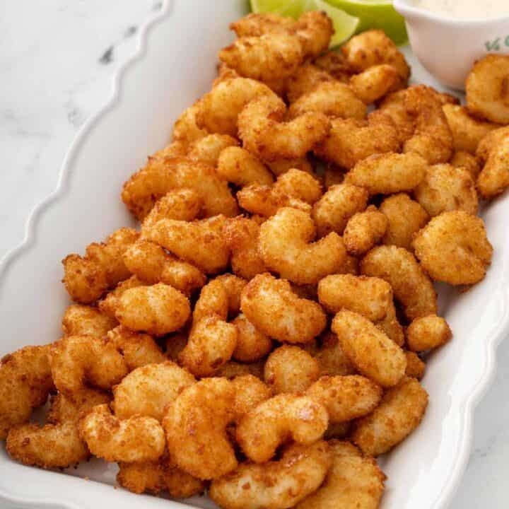 Platter of popcorn shrimp with lime slices and Ranch dipping sauce.
