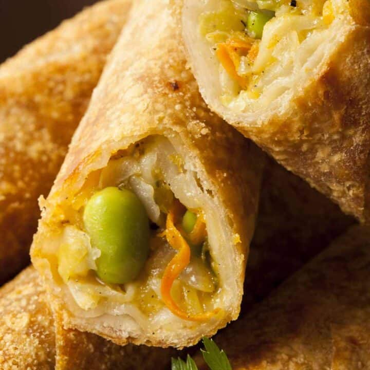 Stack of spring rolls with two cut open to see the ingredients inside.