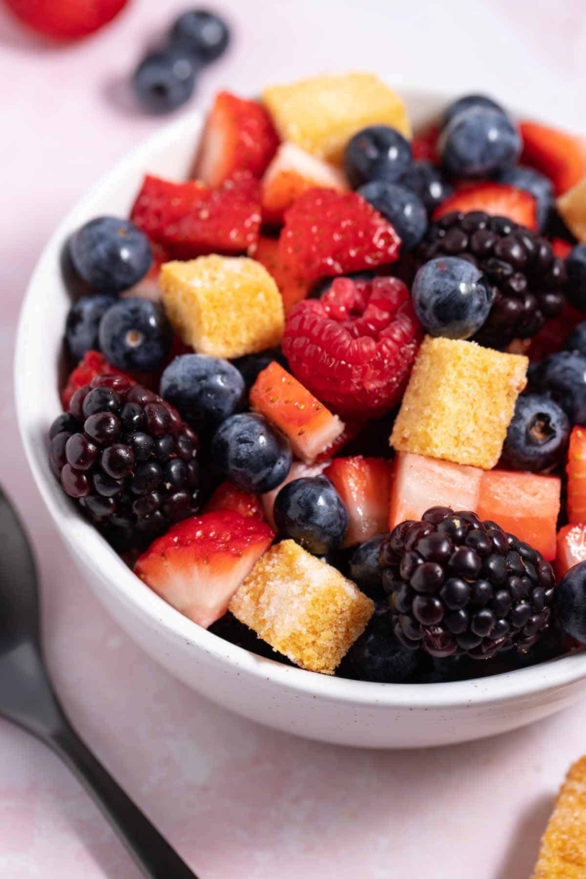 Bowl of berry fruit salad with angel food cake croutons mixed in.