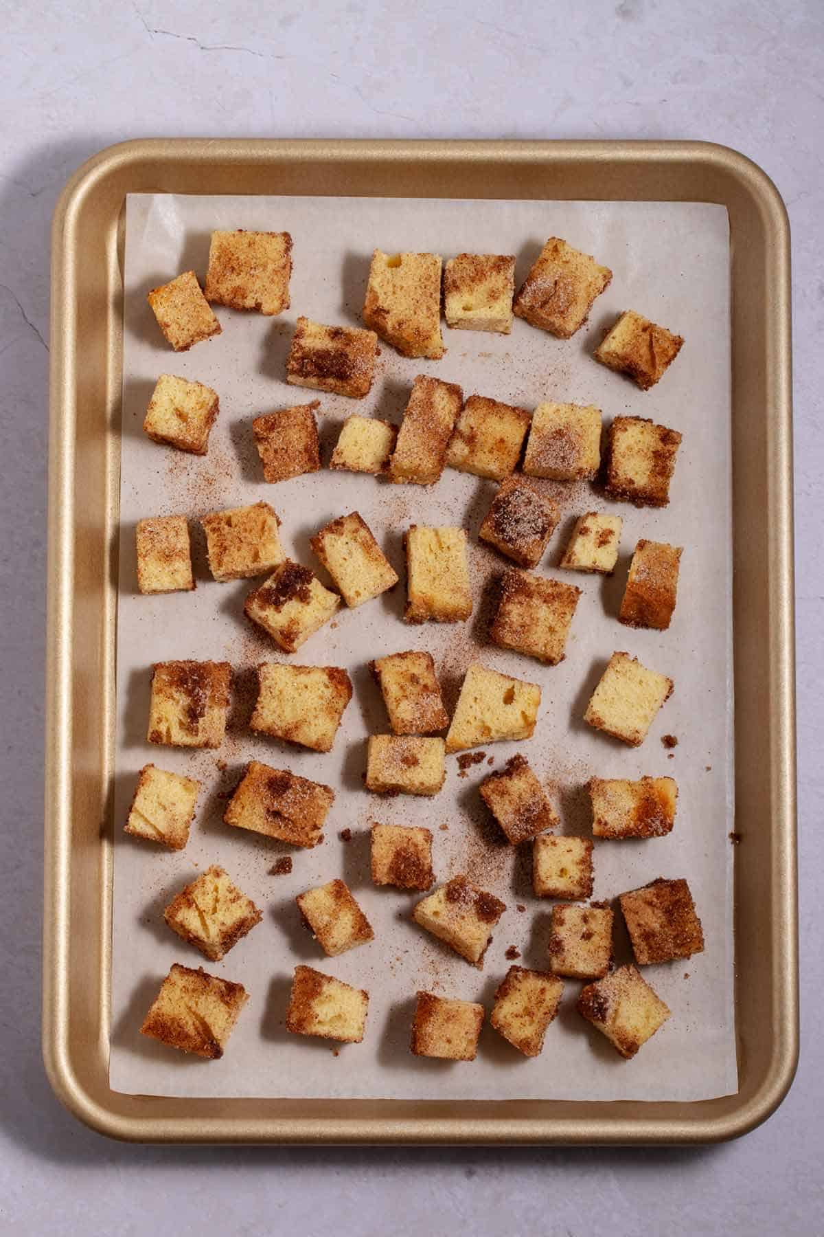 Cinnamon sugar pound cake croutons on a baking sheet.