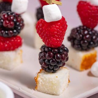 Serving plate filled with dessert skewers with fruit, marshmallows, and leftover cake cubes.