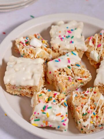 Plate of leftover birthday cake Rice Krispies treats decorated with white chocolate and jimmies.