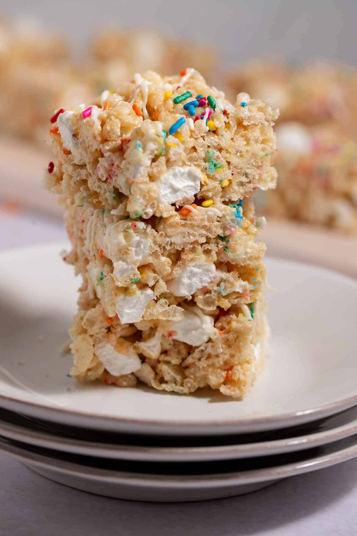 Stack of 3 leftover birthday cake Rice Krispies treat on a dessert plate stack.