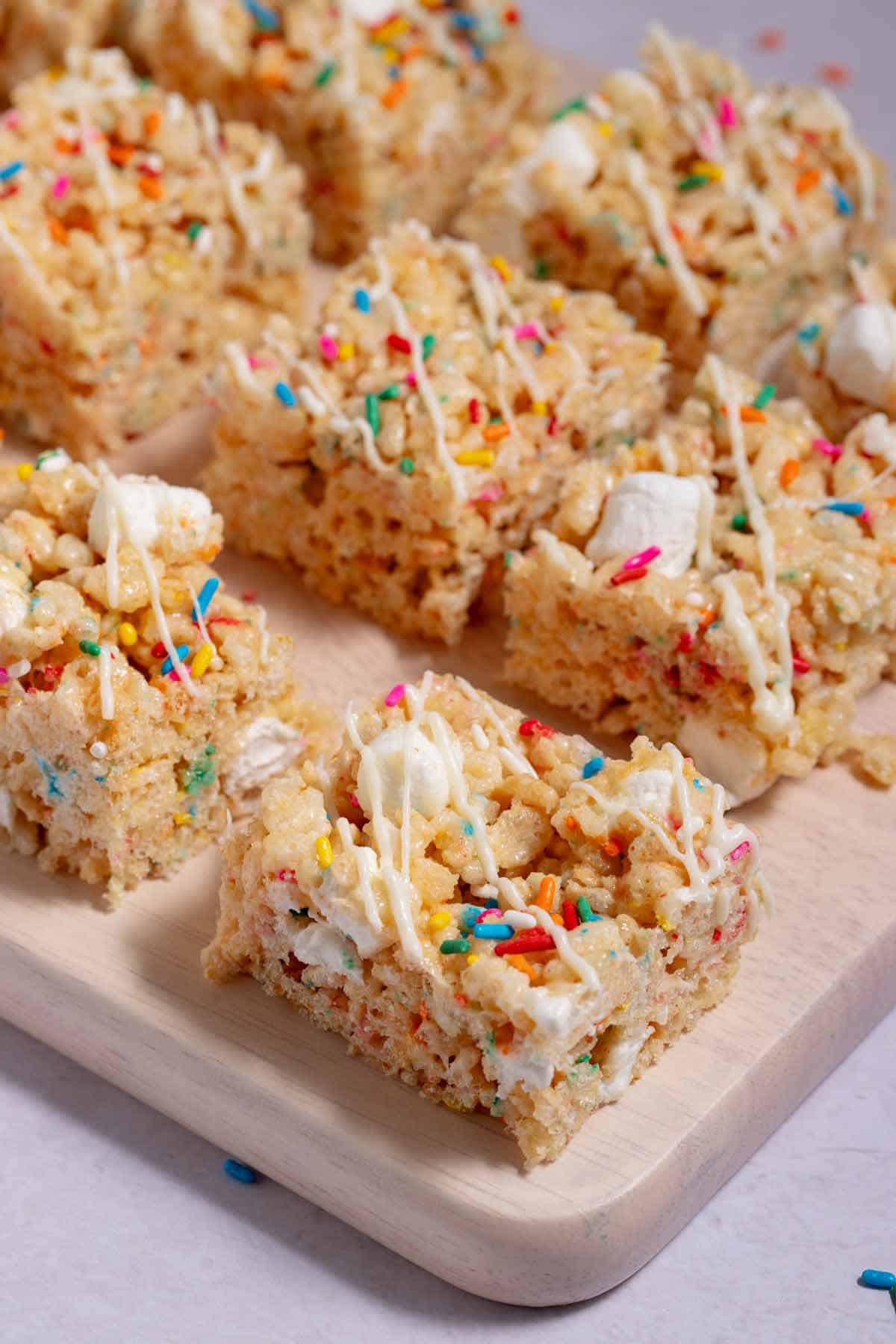 Cutting board filled with leftover birthday cake Rice Krispies treats, cut and drizzled with white chocolate.