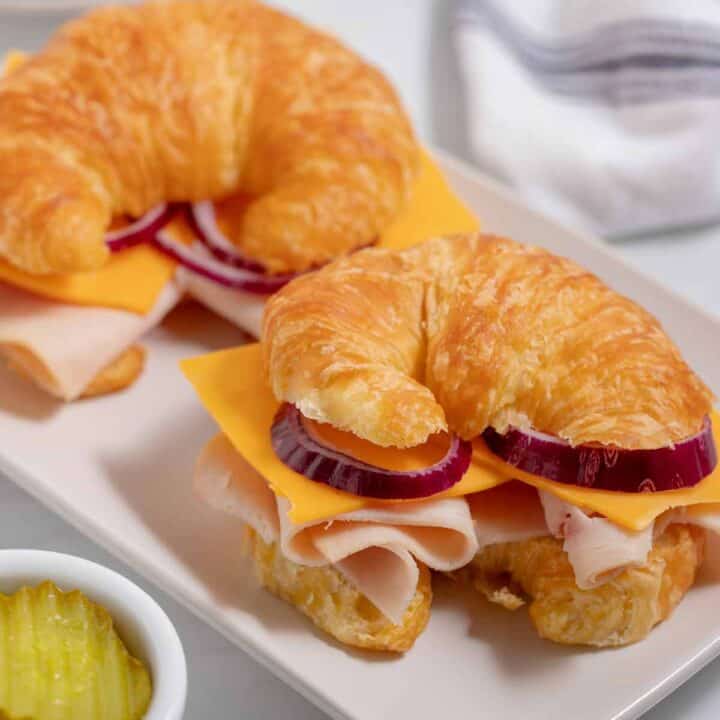 Two turkey sliders on a croissant on a plate.