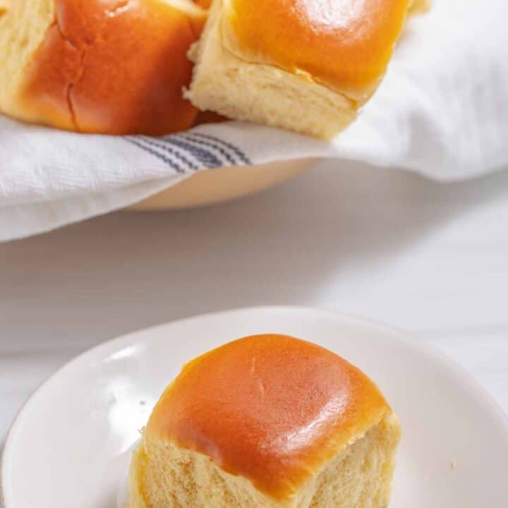 Butter rolls in a bowl and one on a small plate.