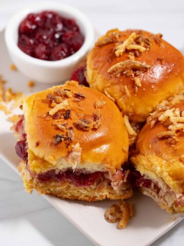 Plate of cranberry turkey sliders with bowl of cranberries.