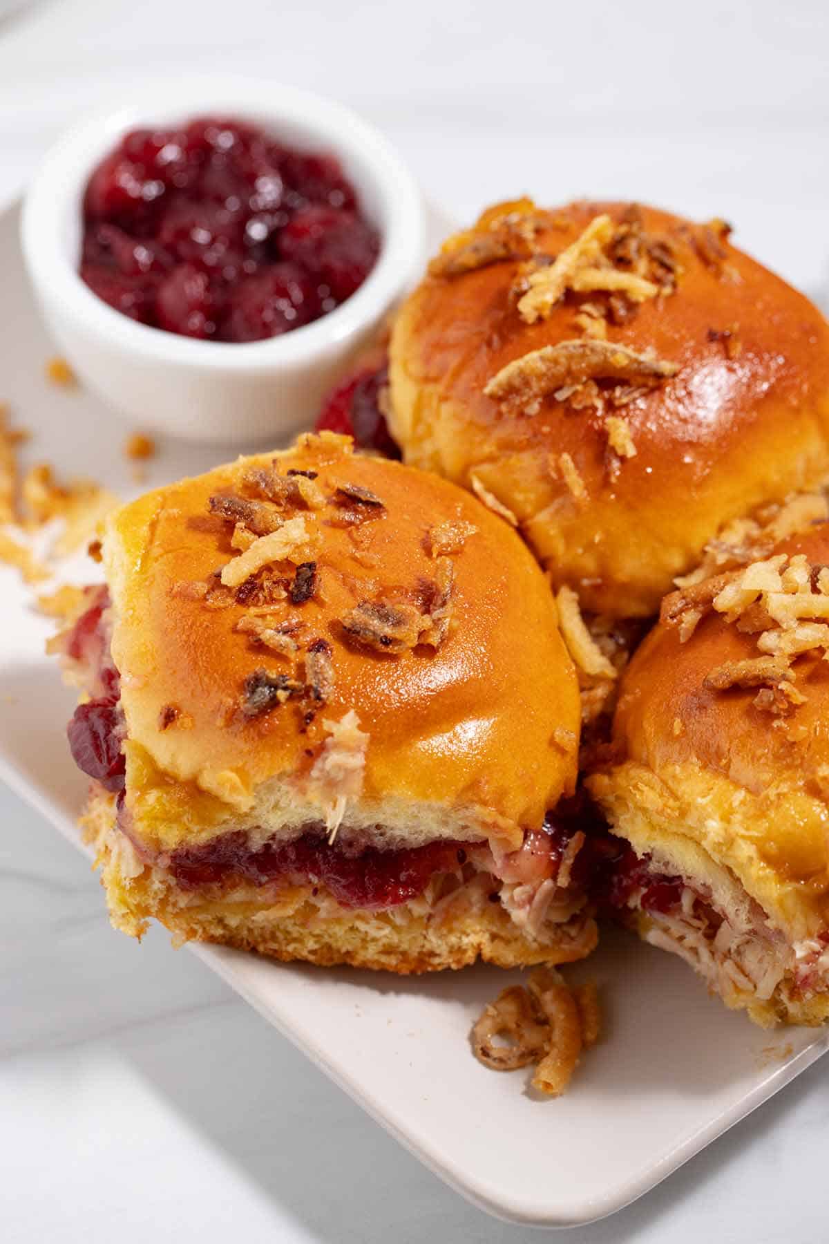 Plate of cranberry turkey sliders with bowl of cranberries.