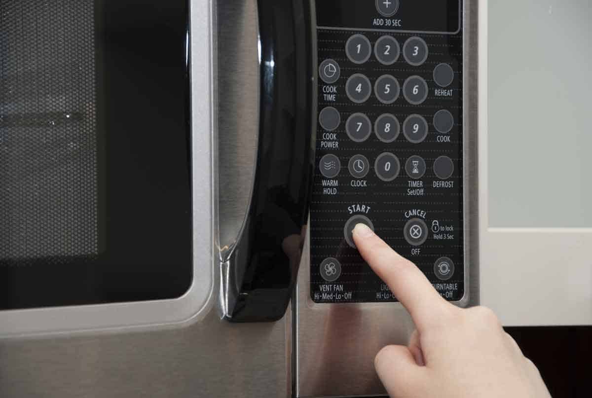 Pushing start button on a microwave.