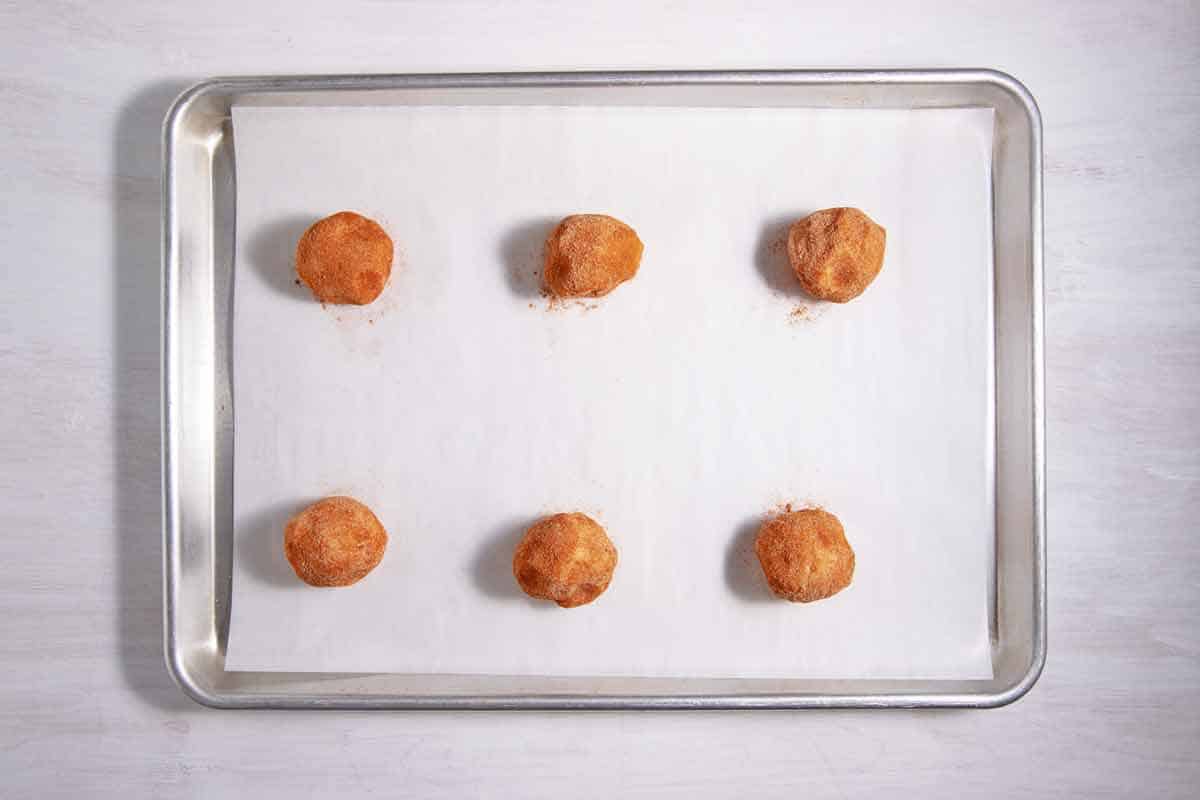 Lined baking sheet with snickerdoodle cookie dough balls.