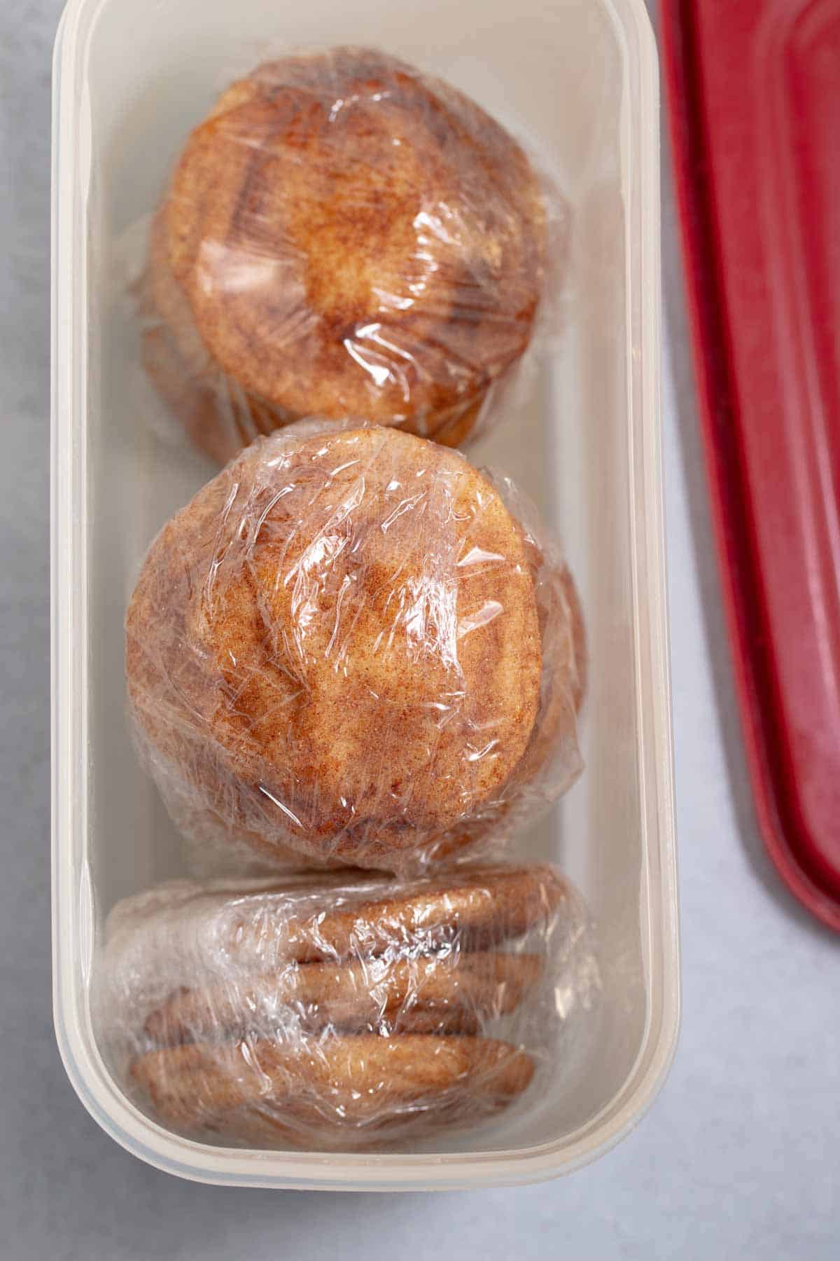 Snickerdoodles wrapped in plastic wrap and set in a container to rest.