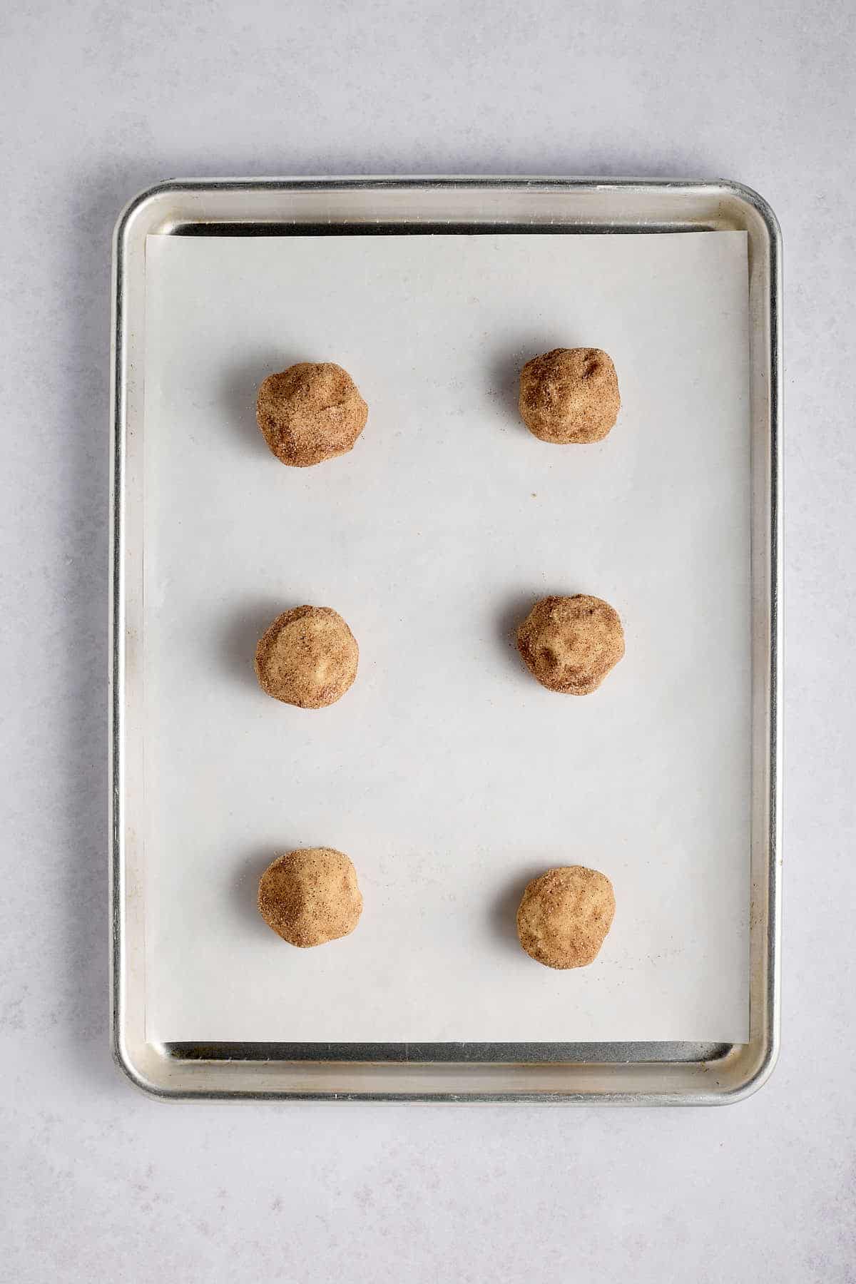 Cookie sheet filled with raw cookie dough balls.
