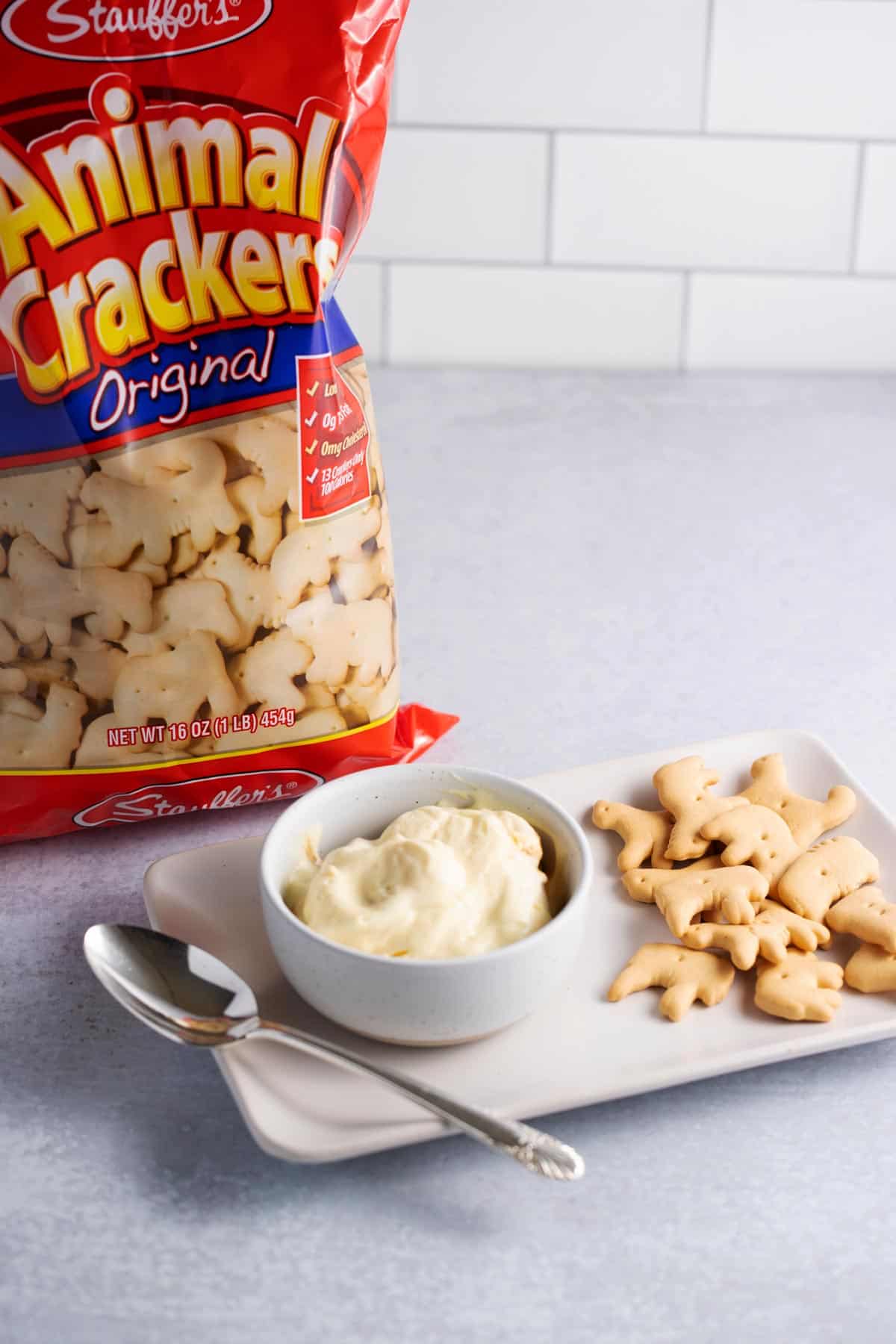 A bowl of banana pudding made with animal crackers with a package of animal crackers in the background.