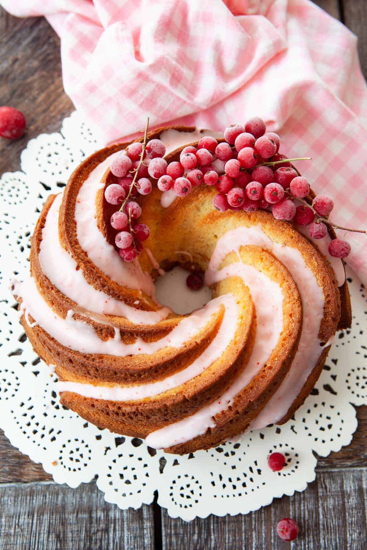 Minimalist Bundt cake with glaze running down the indentations. Fresh berries top a portion of the cake.