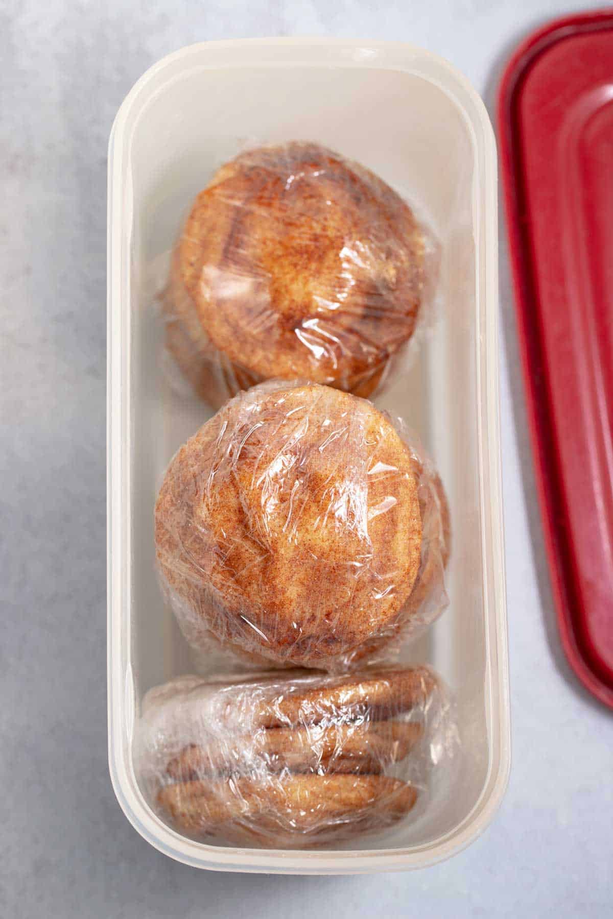 Cookies wrapped in plastic wrap and then placed in an airtight container for storage.