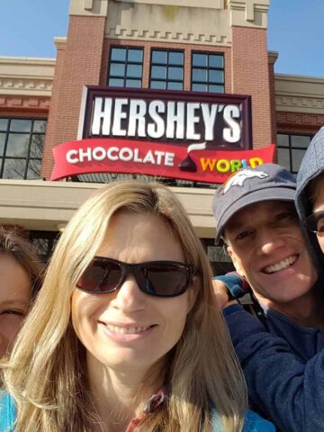 Family standing in front of Hershey's Chocolate World with the sign in clear view.